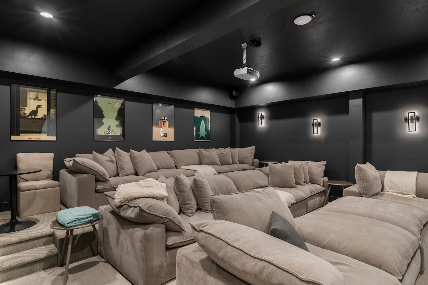 Dark theater room with projector and tiered upholstered seating